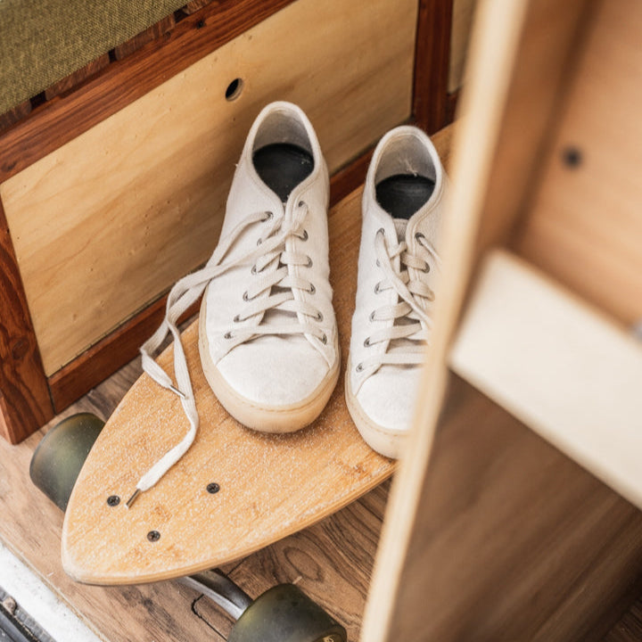 SUM natur Sneaker auf einem hellen Longboard in einem kleinen Zwischenraum in einem Camper umgeben von Schubfächern 