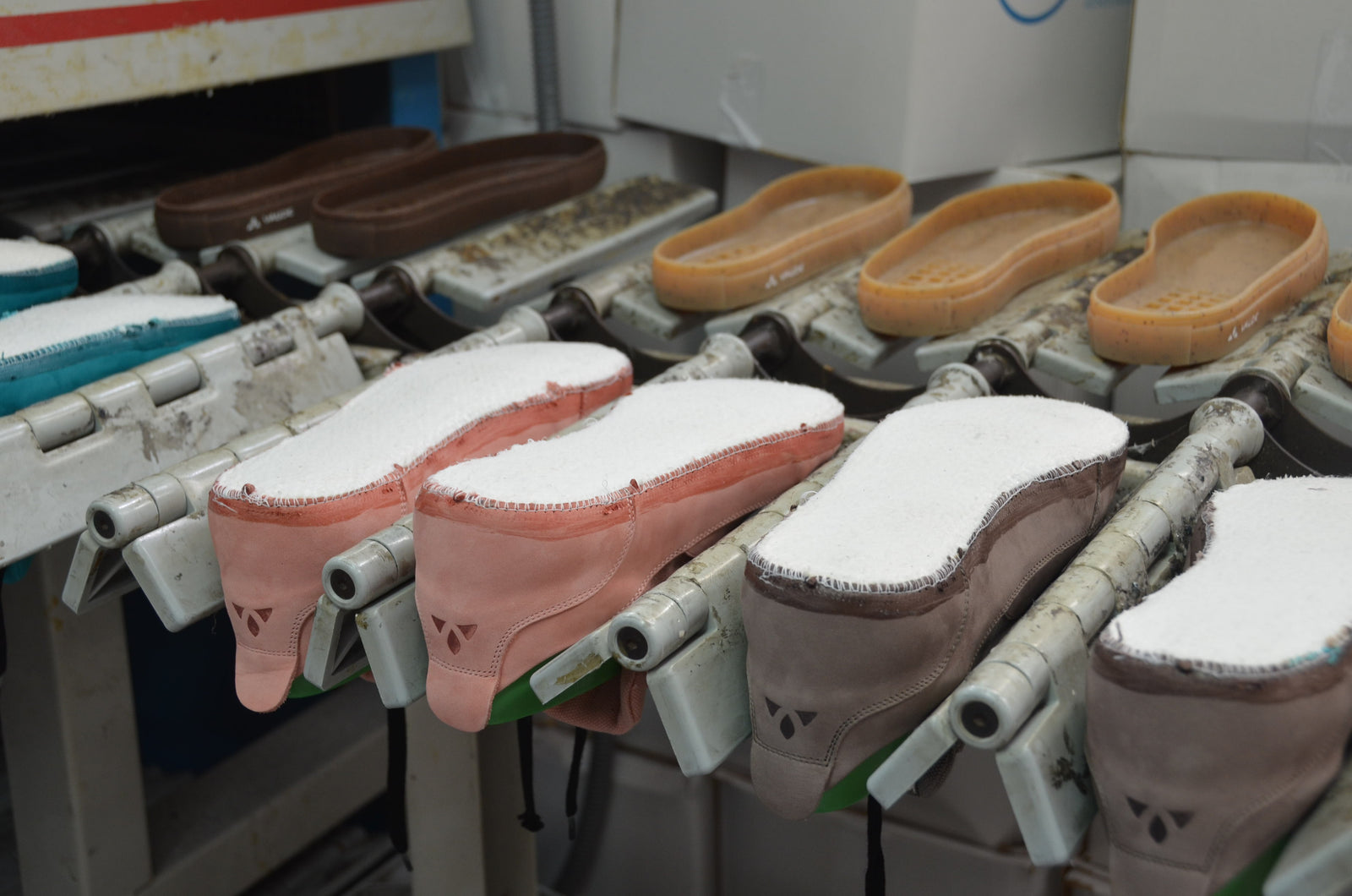 Schuhe in verschiedenen Farben und die dazugehörigen Sohlen auf einem Produktionsband 