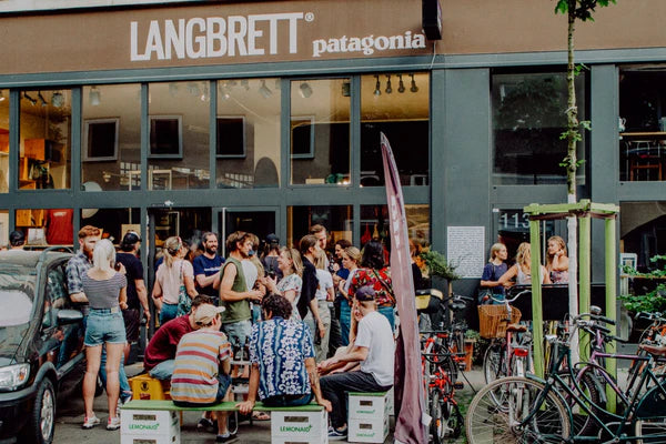 Viele Menschen stehen und sitzen vor einem Langbrett Patagonia Store und unterhalten sich 